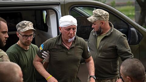 Ukrainische Soldaten helfen einem verwundeten Kameraden an einem medizinischen Stabilisierungspunkt in der Nähe von Bachmut.