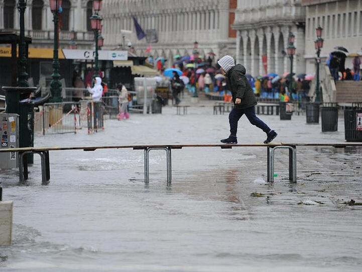 Das Wasser in Venedig steigt wieder: Ein Junge geht auf einem Steg über den überfluteten Markusplatz.