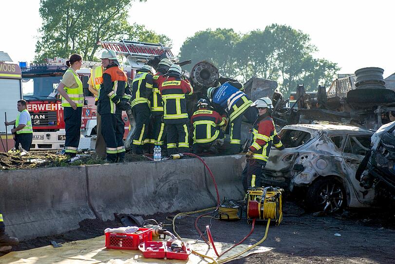 Rettungskräfte auf der Autobahn A8 bei Sulzemoos (Oberbayern) an einem ausgebrannten Lastwagen. Zwei weitere Autos sind in den Auflieger des Lastwagens gefahren. Bei dem Unfall kam mindestens eine Person ums Leben.