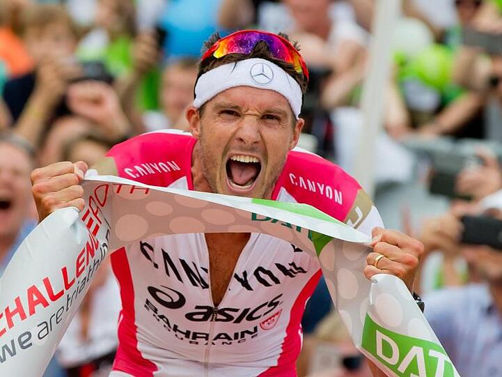 Der deutsche Triathlet Jan Frodeno überquert als Erster die Ziellinie. Foto: Daniel Karmann/dpa/Archivbild