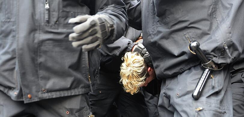 Polizisten nehmen in Berlin einen Demonstranten fest, der gegen Zwangsräumung von Wohnungen in Neukölln protestiert.