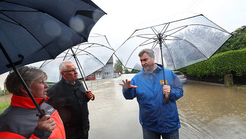Markus Söder (CSU, r), bayerischer Ministerpräsident und Joachim Herrmann, bayerischer Innenminister (CSU, M) stehen am Rande einer überfluteten Straße in Diedorf. Markus Söder (CSU, r), bayerischer Ministerpräsident und Joachim Herrmann, bayerischer Innenminister (CSU, M) stehen am Rande einer überfluteten Straße in Diedorf.