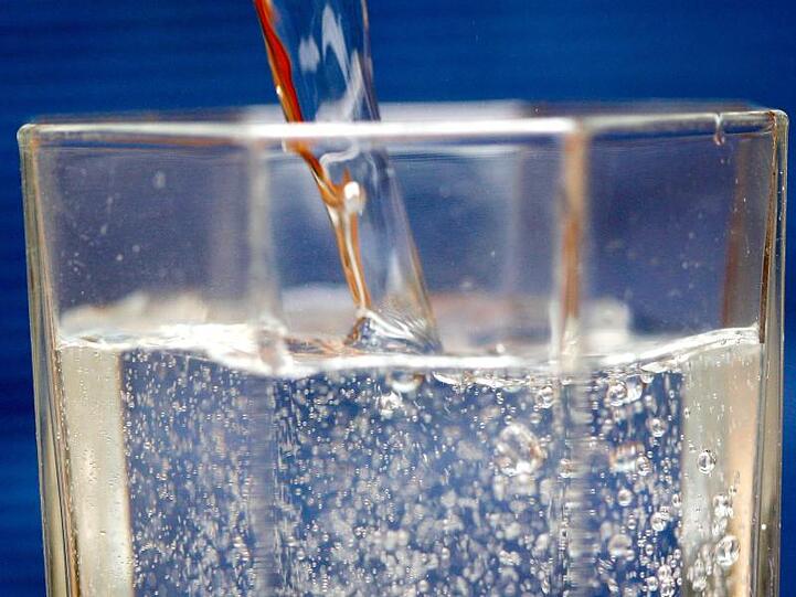 Mineralwasser wird in ein Wasserglas gegossen. Foto: Roland Weihrauch/dpa