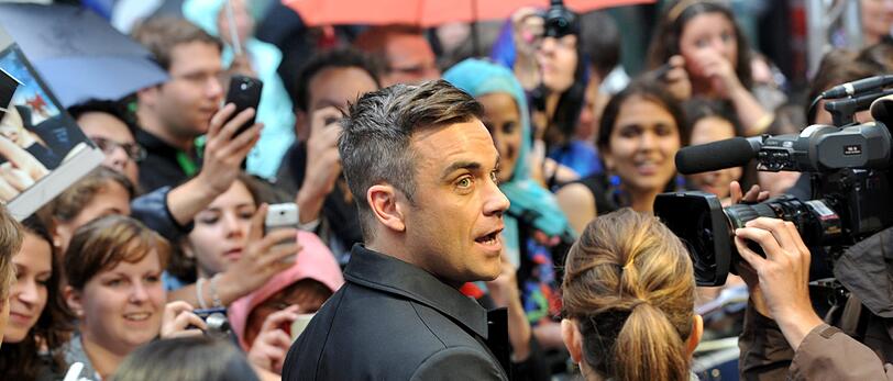 Weltstar im Fan-Gewusel: Robbie Williams verteilte Autogramme vor dem Mathäser-Kino.