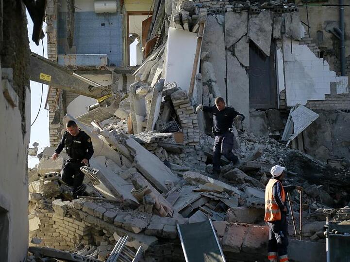 Nach einem Erdbeben durchsuchen Rettungskräfte ein zerstörtes Gebäude.