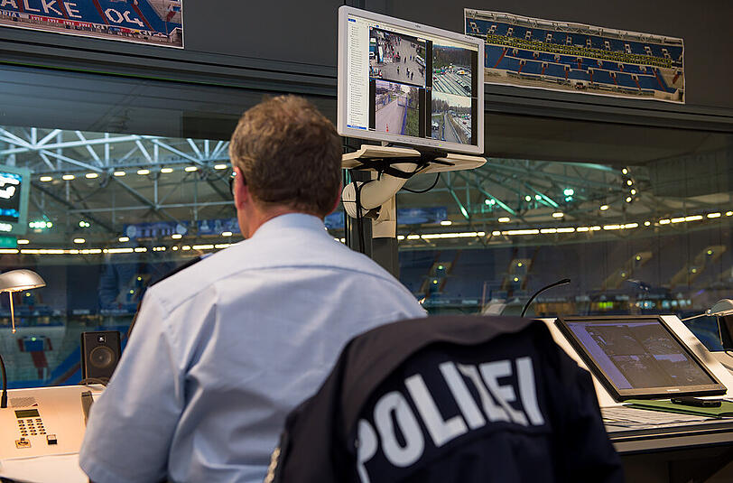 Ein Polizeibeamter sitzt in der Polizei-Leitstelle der Videoüberwachung in der Veltins Arena beim Spiel zwischen dem FC Schalke 04 und dem FC Bayern.