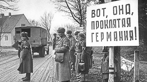 Irgendwo in Ostpreußen im Januar 1945: Sowjetische Armeeangehörige befinden sich im Deutschen Reichsgebiet. Auf dem Schild steht sinngemäß: "Bitte sehr, das verdammte Deutschland".