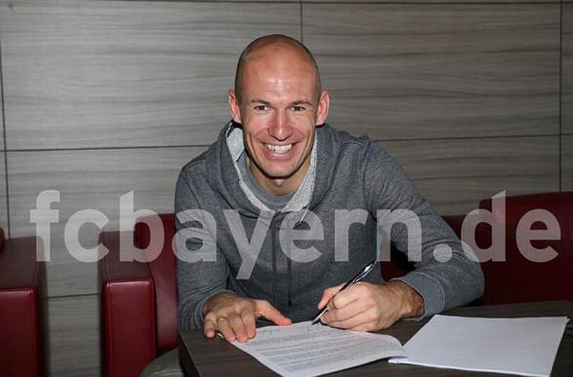 Arjen Robben lächelt, setzt seine Unterschrift unter einen neuen Vertrag beim FC Bayern München.