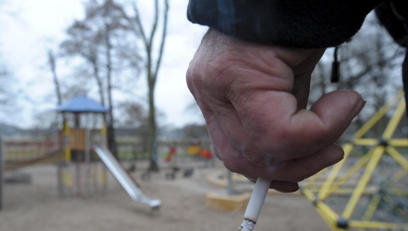Ein Mann hält auf einem Spielplatz eine Zigarette in der Hand. Ein Mann hält auf einem Spielplatz eine Zigarette in der Hand.