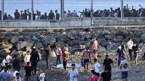 Beamte der Guardia Civil und Mitglieder des Roten Kreuzes beobachten Menschen aus Marokko, die die Grenze überquert haben.