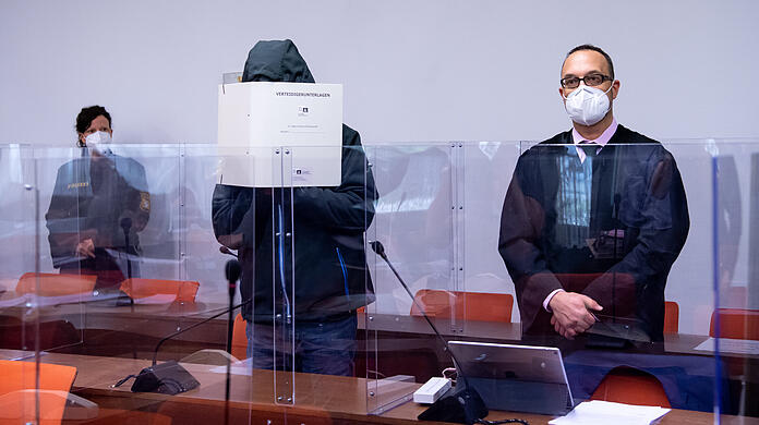 Der Angeklagte steht vor Prozessbeginn im Landgericht neben seinem Anwalt Adam Ahmed.