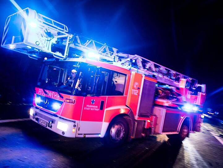 Ein Drehleiterwagen der Feuerwehr fährt mit Blaulicht an einer Unfallstelle vorbei. Foto: Marcel Kusch/dpa/Illustration