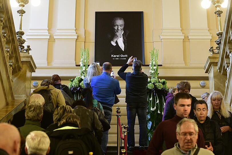 Fans stehen im Prager Sophienpalais und fotografieren ein Porträt des Sängers Karel Gott.