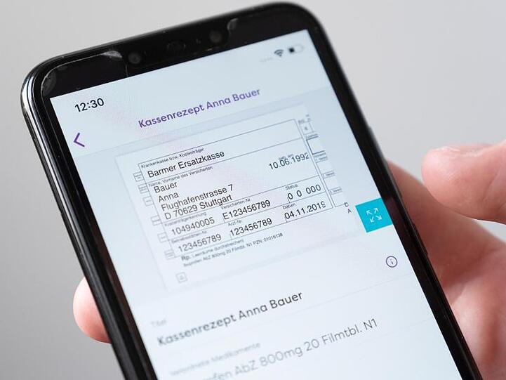 Auf einem Smartphone wird in einer App ein digitales Rezept einer fiktiven Patientin dargestellt.