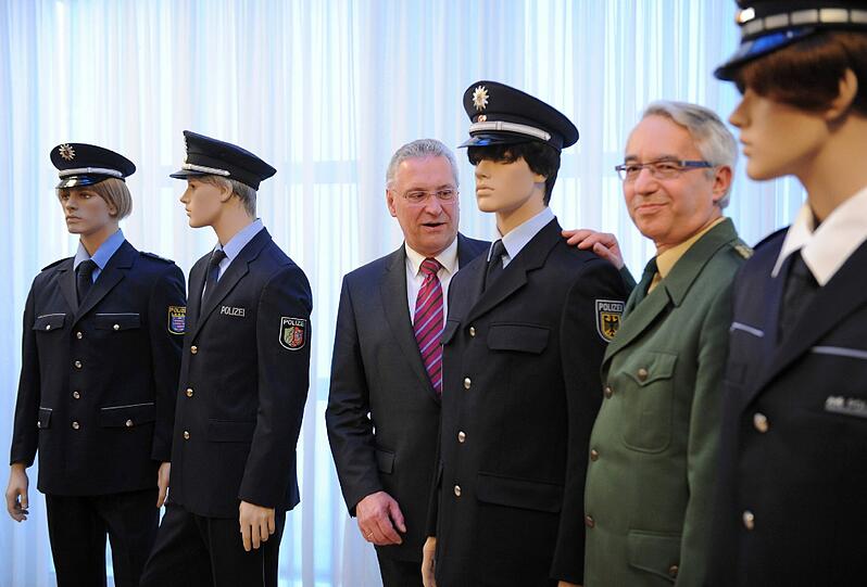 Der bayerische Innenminister Joachim Herrmann und Landespolizeipräsident Wilhelm Schmidbauer zwischen Puppen mit den Polizeiuniformen von Thüringen (l-r), Nordrhein-Westfalen, Bundespolizei und Baden-Württemberg.