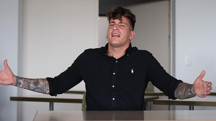 Rapper Gzuz (bürgerlich Kristoffer Jonas Klauß) gestikuliert vor Prozessbeginn im Gerichtssaal. Angeklagt ist er unter anderem wegen Verstößen gegen das Waffengesetz, versuchtem Diebstahl und Körperverletzung.