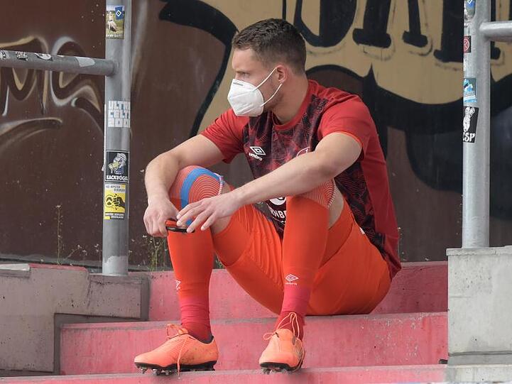 Nürnbergs Torwart Christian Mathenia sitzt nach seiner Roten Karte mit Maske auf der Tribüne. Foto: Axel Heimken/dpa - Pool/dpa/Archivbild