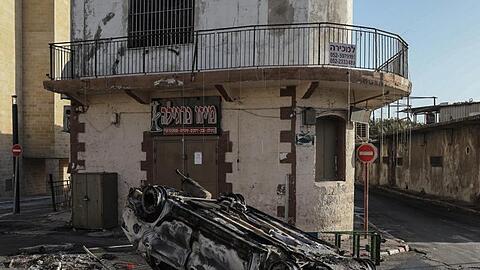 Ein verbranntes Auto liegt nach Zusammenstößen zwischen Polizisten und arabischen Israelis auf einer Straße in Lod, rund 20 Kilometer östlich von Tel Aviv.