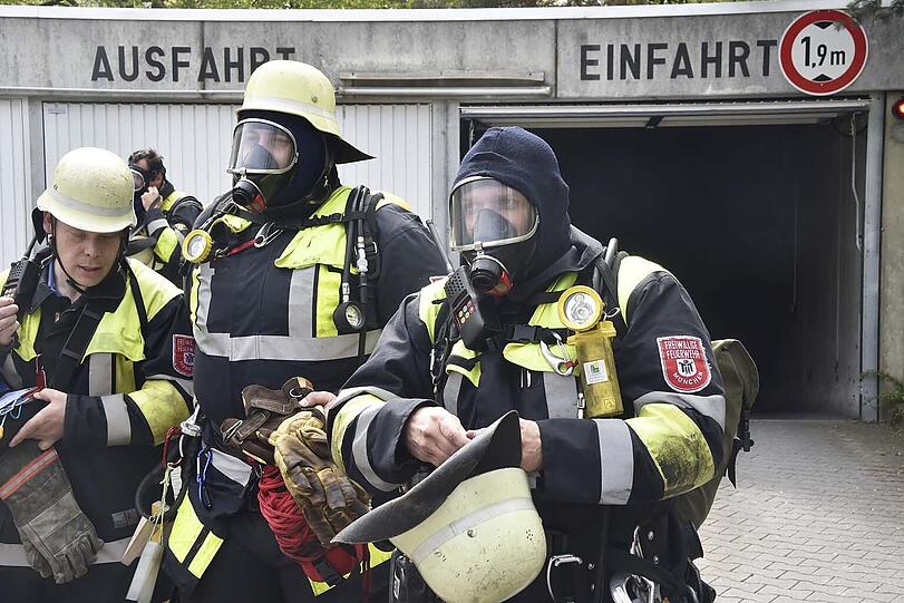 Nach dem Brand: Feuerwehrmänner verlassen am Samstag mit Gasmasken die Tiefgarage in der Von-Knoeringen-Straße.