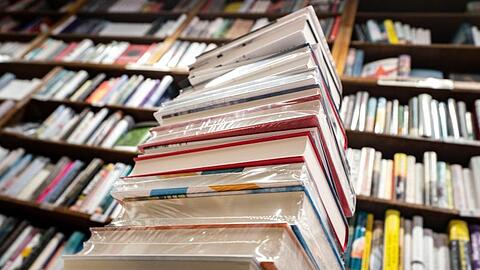 Ein Stapel neuer Bücher liegt auf einem Verkaufstisch in einer Buchhandlung.