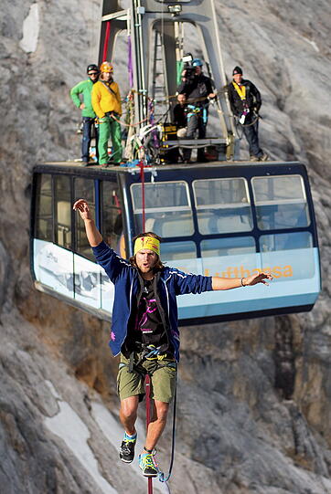 Atemberaubende Bilder. Alexander Schulz (23) aus Rosenheim ist in schwindelerregender Höhe über eine Slackline zwischen zwei Zugspitz-Gondeln hin und her balanciert.