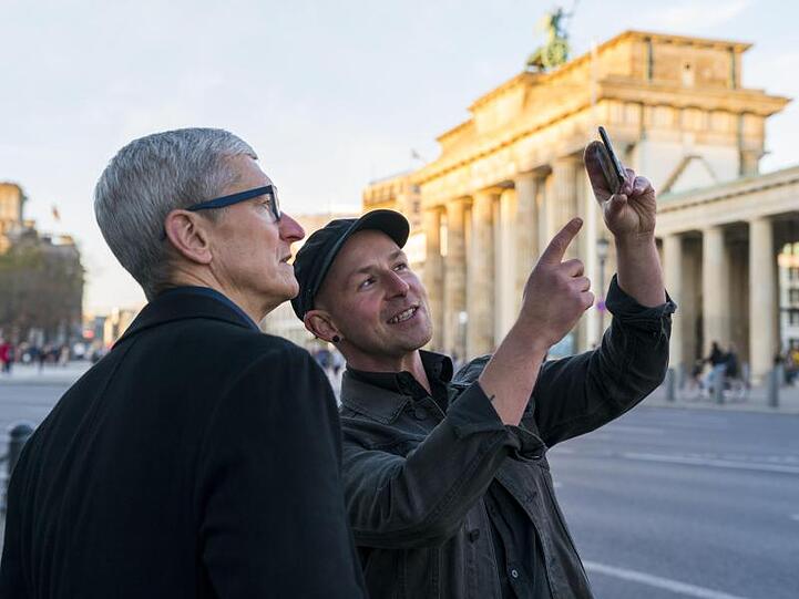 Apple-Chef Tim Cook (l) lässt sich am Brandenburger Tor von Entwickler Peter Kolski das Projekt "MauAR" erklären.