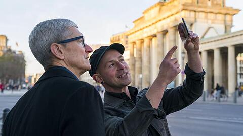 Apple-Chef Tim Cook (l) lässt sich am Brandenburger Tor von Entwickler Peter Kolski das Projekt "MauAR" erklären.