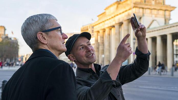 Apple-Chef Tim Cook (l) lässt sich am Brandenburger Tor von Entwickler Peter Kolski das Projekt "MauAR" erklären.