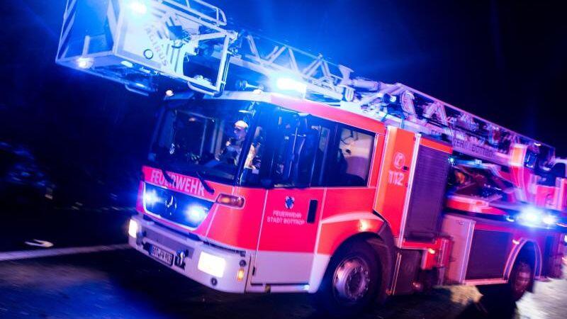 Ein Drehleiterwagen der Feuerwehr fährt mit Blaulicht über eine Straße.