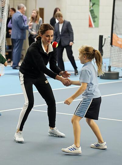 Herzogin Kate gibt einem Mädchen im Tennis Centre in London die Hand. Im Schwarz-Weiß-Outfit tritt sie bei der Veranstaltung "Tennis for Kids" gegen eine Teilnehmerin an.