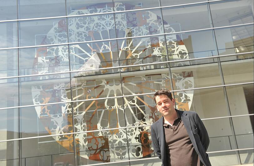 Martin Wöhrl vor seiner Arbeit &bdquo;Maß und Werk&ldquo; in der Fassade des Neuen Museums.