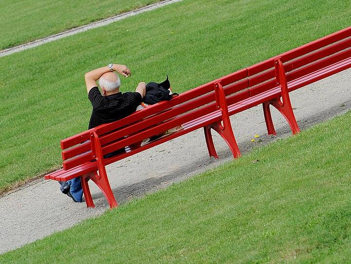 Ein Mann genießt auf einer Bank das spätsommerliche Wetter