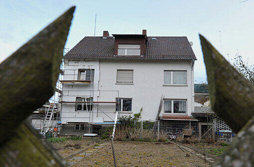 Blick durch den Gartenzaun auf ein Mehrfamilienhaus in einem Ort im hessischen Kreis Gießen am Mittwoch (25.04.2012). In einer zu dem Haus gehörenden Garage und einem Kellerraum waren nach Polizeiangaben die Leichen von drei Säuglingen in Camping-Kühlboxen gefunden worden, als die Wohnung einer 40 Jahre alten Frau aufgelöst wurde.