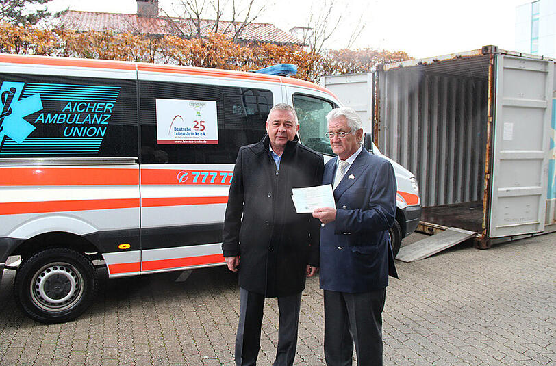 Peter Aicher (l.) und Reinhard Mayer beim Verladen des Sanitätswagens in den Übersee-Container.