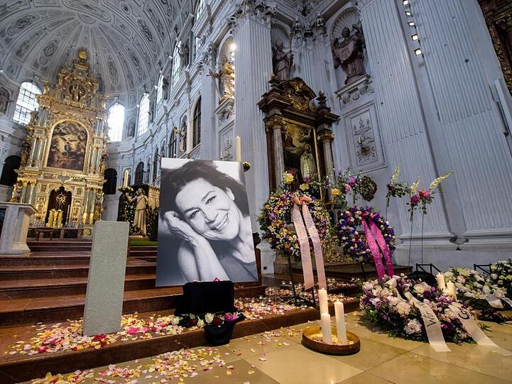 Kerzen, Blütenblätter, Kränze und ein Porträt von Hannelore Elsner in der Kirche St. Michael in München.