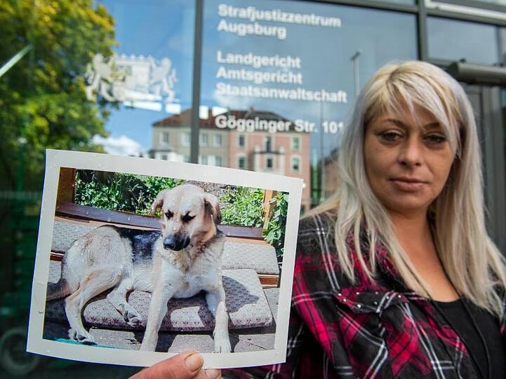 Die Hundebesitzerin steht mit einem Foto ihres Hundes Maja vor dem Strafgerichtsgebäude. Foto: Stefan Puchner/dpa