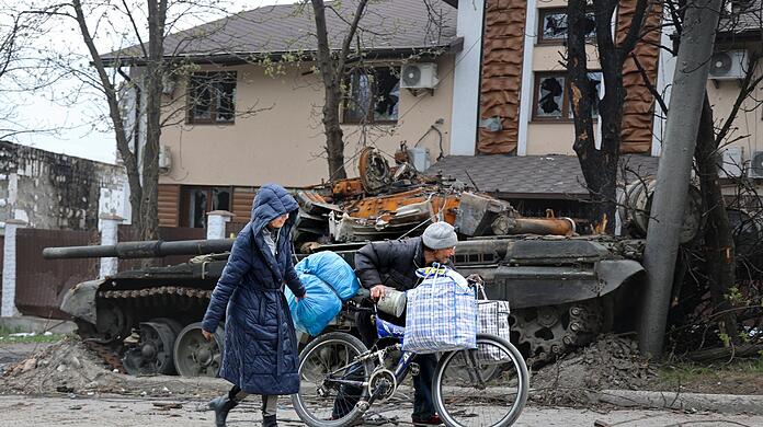 Zivilisten gehen in Mariupol an einem Panzer vorbei, der bei schweren K&auml;mpfen zerst&ouml;rt wurde.