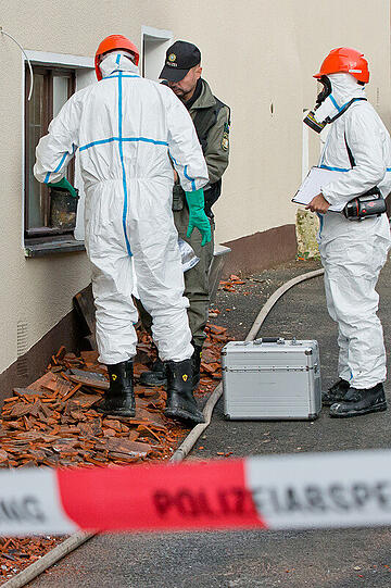 Mitarbeiter der Spurensicherung stehen am 12.12.2014 in Vorra (Bayern) an einem durch einen Brand beschädigtem Gebäude. In der Nacht hatten im Ortskern des Dorfes im Kreis Nürnberger Land ein ehemaliger Gasthof, ein nahe gelegenes Wohnhaus sowie eine Scheune gebrannt. In die Gebäude sollten in der kommenden Woche Asylbewerber einziehen.