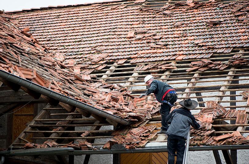 Aufräumarbeiten nach dem Tornado: Dachdecker räumen in Dramfeld im Landkreis Göttingen Ziegel von einem Scheunendach. Foto: Swen Pförtner