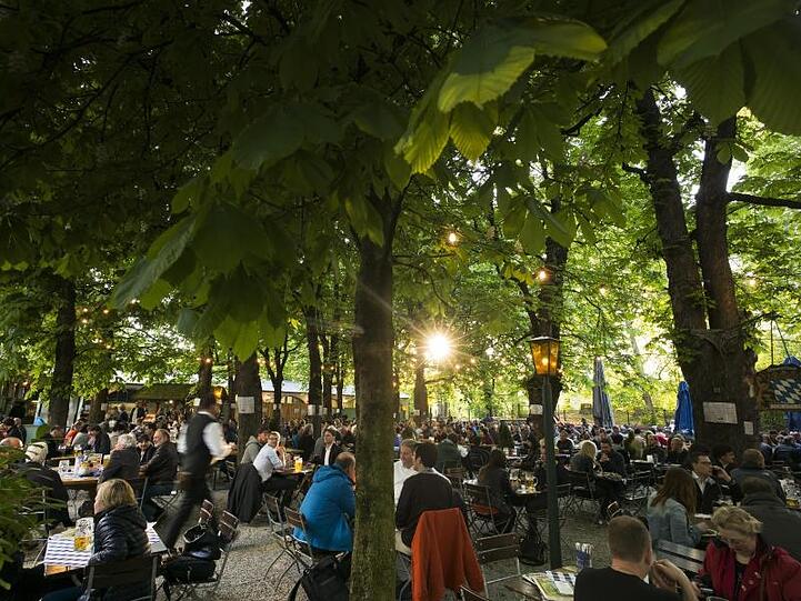 Besucher genießen im Biergarten den Sonnenuntergang. Foto: Peter Kneffel/Archiv