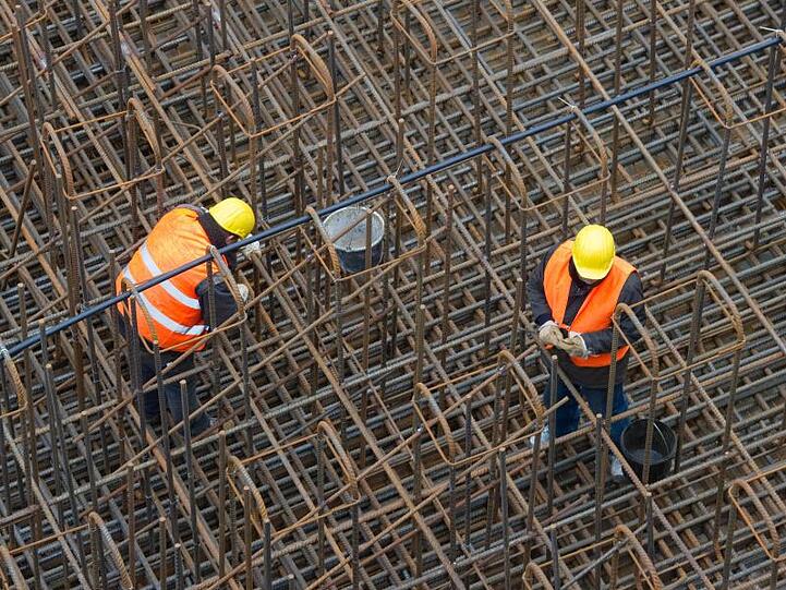 Bauarbeiter errichten auf einer Baustelle ein Stahlgeflecht.