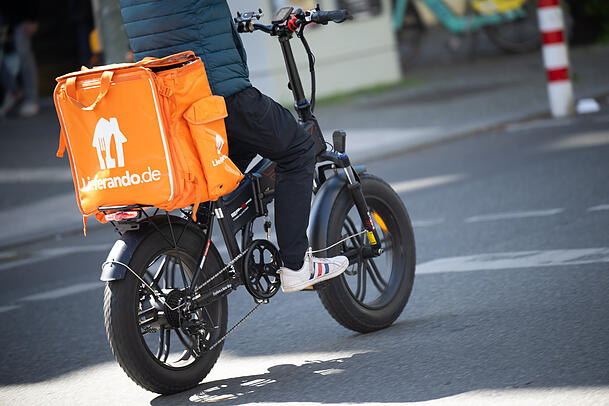 Ein Fahrer für den Essenslieferdienst Lieferando fährt über eine Straße. In München wird im bayernweiten Vergleich unterdurchschnittlich Trinkgeld gegeben.