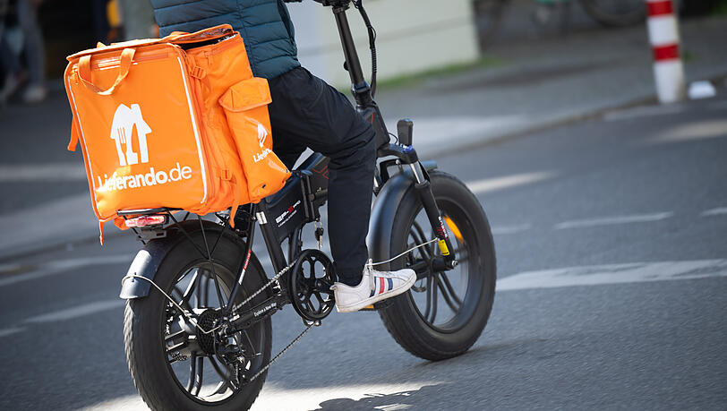 Ein Fahrer für den Essenslieferdienst Lieferando fährt über eine Straße. In München wird im bayernweiten Vergleich unterdurchschnittlich Trinkgeld gegeben.
