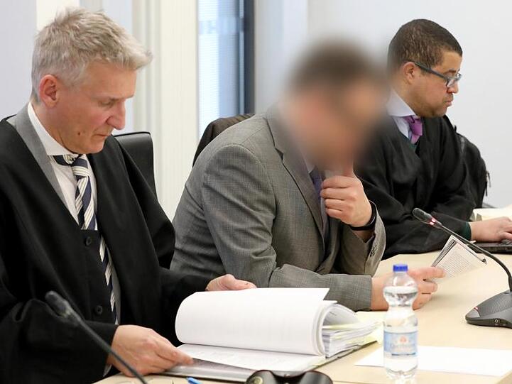 Der angeklagte Neurochirurg (M) mit seinen Anwälten im Rostocker Landgericht.