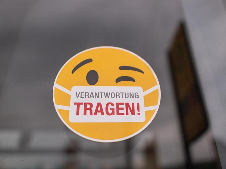 Ein Smiley-Aufkleber "mit Mundschutz" an der Scheibe einer Straßenbahn.