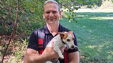 Ein Feuerwehrmann h&auml;lt Jack Russell Terrier Spencer im Arm.