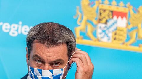 Markus Söder (CSU) setzt sich nach einer Pressekonferenz seine Gesichtsmaske auf. Foto: Peter Kneffel/dpa/Archivbild
