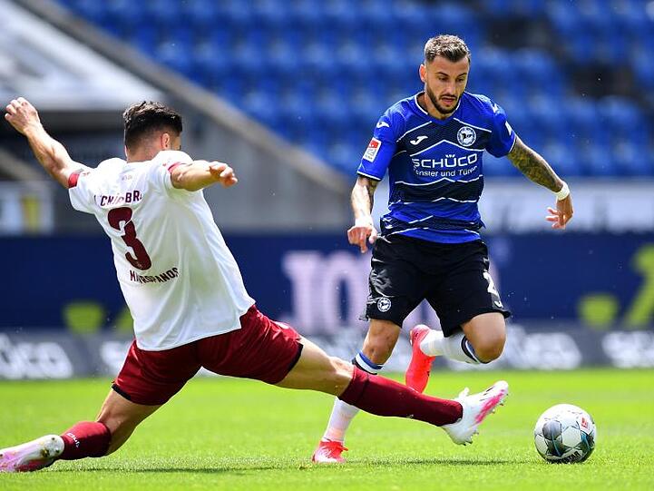 Der Nürnberger Konstantinos Mavropanos (l) grätscht in den Lauf von Arminia-Spieler Jonathan Clauss.