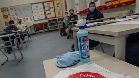 Ein Schild mit der Aufschrift "Bitte sitzen bleiben!" liegt auf einem Tisch im Klassenraum einer vierten Klasse. Foto: Peter Kneffel/dpa