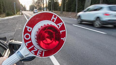 Ein Polizist hält eine Polizeikelle. Foto: Armin Weigel/Archiv